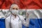 Young woman doctor in medical uniform on the background of the national flag of Paraguay is holding a syringe. The concept of a