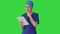 Young woman doctor or nurse in scrubs using a touchscreen computer while walking on a Green Screen, Chroma Key.