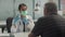 A young woman doctor offers her elderly patient to be vaccinated against influenza and coronavirus, holding a bottle of