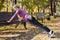 Young woman does push-up exercises in the park. Sports outside in autumn