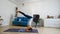 Young woman does yoga at home bending knees to her chest in pindasana pose