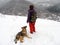 Young woman with dog on top of snowy hill