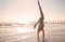 Young woman doing acrobatic exercise on coast of sea on beach