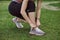 A young woman doing exercises outdoors on green grass. Fitness sporty girl tightening her sneakers