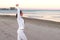 Young woman is doing exercises to restore breathing on the sand beach at sunrise in autumn, back view.