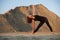 young woman doing extended triangle yoga pose outdoors