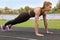 Young woman doing high plank exercise at stadium