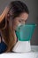 Young woman doing inhalation with a medical vaporizer nebulizer machine on grey background