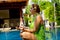 Young woman doing meditation at the pool in bali island