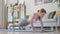 Young woman doing pushups on yoga mat at home