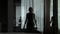 Young woman doing star jumps in the living room. Slow motion silhouette reflection in the glass window. Healthy and