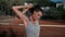 Young woman doing warm-up of upper body in stadium on sunny afternoon.