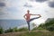 Young woman doing yoga asana. Girl raises one leg and holds it by her hand. Balance yoga pose. Bali, Indonesia