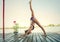 Young woman doing yoga in bikini on wooden river raft