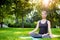 Young woman doing yoga exercises in the summer city park.