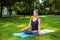 Young woman doing yoga exercises in the summer city park.