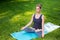 Young woman doing yoga exercises in the summer city park.