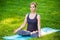 Young woman doing yoga exercises in the summer city park.