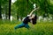 Young woman doing yoga on a green forest.