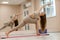 Young woman doing yoga in the gym. A girl with long hair and in a beige tracksuit stands in a parivritta trikonasana