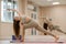 Young woman doing yoga in the gym. A girl with long hair and in a beige tracksuit stands in a parivritta trikonasana