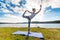 Young woman doing yoga near lake outdoors, meditation. Sport fitness and exercising in nature. Autumn sunset.