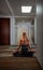 Young woman doing yoga at the office, sand and waves on the floor and clouds in the sky