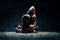 Young woman doing yoga Padmasana pose variation on dark room