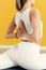 Young woman doing yoga pose, holding her hands in prayer behind her back. Yoga class on a yellow background. The concept