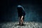 Young woman doing yoga standing forward bend pose in dark room