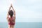 Young woman doing Yoga and stretching muscle in morning, healthy girl meditation against ocean view. wellness, fitness, Vitality,