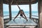 Young woman doing yoga in the wooden gazebo at the beach