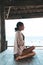 Young woman doing yoga in the wooden gazebo at the beach