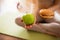 Young woman doing yoga workout in room during quarantine. Cut view of girl holding green healthy apple and fatning