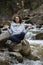 Young woman doing yoga zen on a rock in the middle of the river in a forest