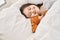 Young woman with down syndrome lying on bed sleeping with teddy bear at bedroom