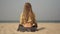 A young woman with dreadlocks is meditating on a beach.