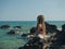 Young woman with dreadlocks sitting on the rocks