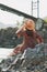 Young woman in dress and felt hat on Horochowski bridge on the Katun river, Altai