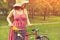 Young woman in a dress and hat with a bike with flowers in a basket