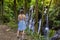 A young woman in a dress at Kanto Lampo waterfall in lush tropical forest, Bali