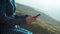 A young woman in a dress sits with a phone in her hands against a background of mountains closeup. The girl travels in