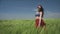 Young woman dressed in Boho style swaying in the middle of green wheat field is catching wind blowing Close her eyes to