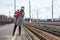 Young woman dressed coat and cap watch the train while standing on station platform