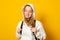 Young woman dressed white hoodie on yellow  background with backpack. Portrait of cool schoolgirl with backpack