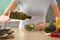 Young woman dressing fresh vegetable salad with olive oil in kitchen, closeup