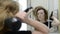 A young woman dries her hair with a hairdryer in the bathroom in front of the mirror