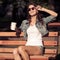 Young woman drinking coffee from paper cup. Sitting on bench