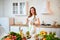 Young woman drinking fresh water from glass and showing thumbs up in the kitchen. Healthy Lifestyle and Eating. Health, Beauty,