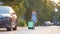 Young woman driver walking down the street pulling green suitcase. Travelling and vacations concept.